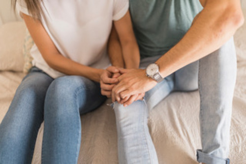 Una pareja sentada y agarrada de la mano