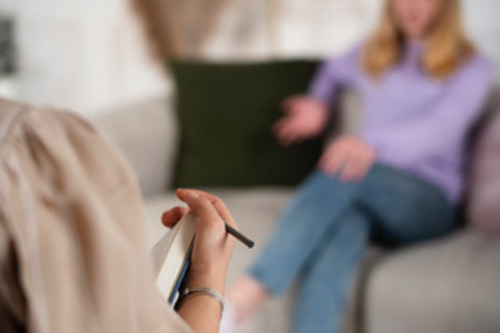 Una psicologa con un cuaderno y pasando consulta a una adolescente